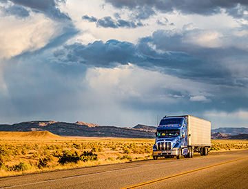 A semi trailer drives on a U.S. highway, hauling freight through the desert.