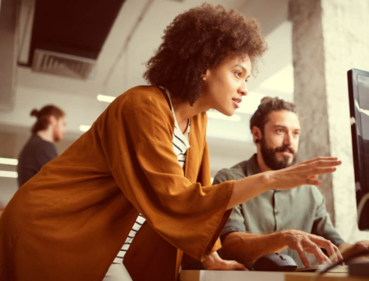 Image of two colleagues looking at a computer in a modern office.