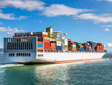 Image shows ship with shipping containers.