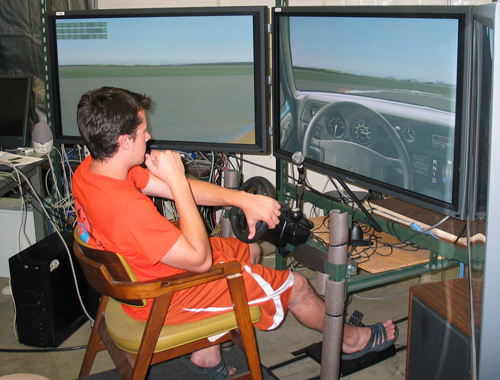 A Summer Transportation Institute student tests the Airport Surface Low Cost Driving Simulator during his visit to the Volpe’s Human Factors Laboratory. (Volpe photo) A Summer Transportation Institute student viewing a simulator screen