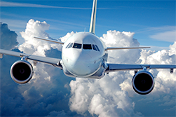 A commercial airliner in flight over a cloud-covered background.