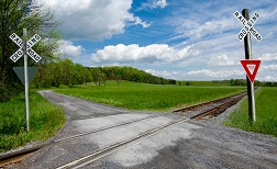 A narrow gravel road crosses over a railroad track.