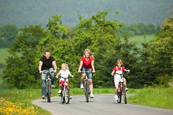 A family of four out on a bike ride down a bike path.