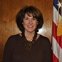 This is an image of Jane Lappin standing beside an American flag.
