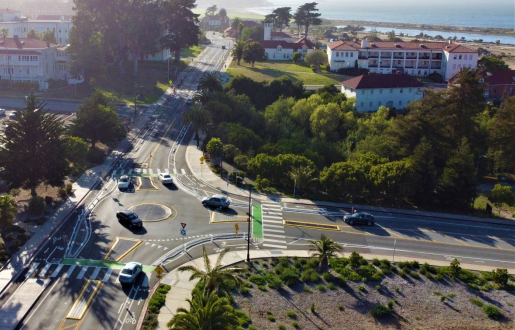 Cars proceed through an intersection that has a mini roundabout at its center.