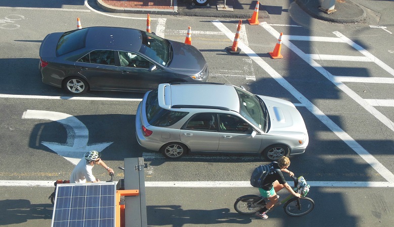 An intersection with cars and bicyclists waiting at a light.