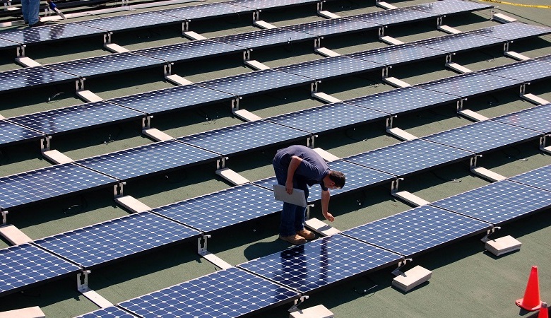 A man installing solar panels on a roof