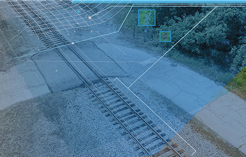 A photo of a highway-rail grade crossing with graphical overlays that indicate the crossing's height and identify rail assets such as crossing signage.