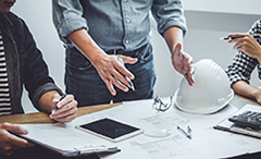 An image of several workers studying a construction plan in a modern office.