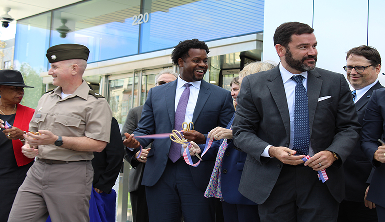 Leaders smiling and holding the cut ribbon outside the new facility