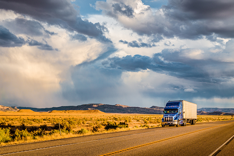 A semi trailer drives on a U.S. highway, hauling freight through the desert.