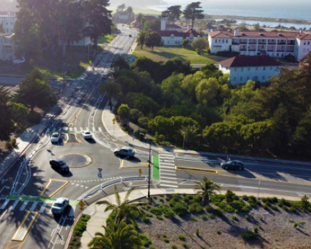 Cars proceed through an intersection with a mini roundabout.
