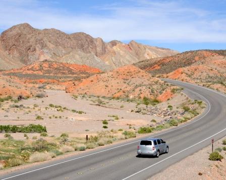 An image of a silver vehicle on a desert highway.