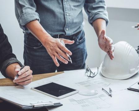 An image of several workers studying a construction plan in a modern office.