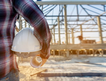 Man holding construction hat looking at a project site.