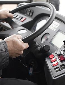 A bus driver's hands on a steering wheel