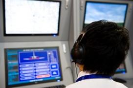 A flight controller looking at screens in a flight control tower.