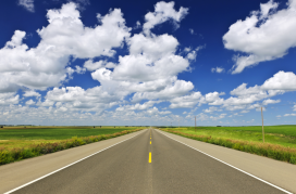 A long stretch of flat highway in the Canadian Saskatchewan prairies.