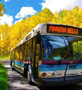 Image of bus with Maroon Bells on bus screen and yellow foliage in the background.