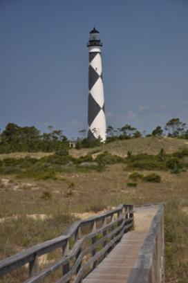 Black and white striped lighthouse with dock in front at the Cape Lookout National Seashore.