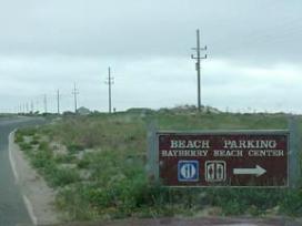 A sign for beach parking on the side of a road